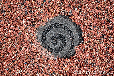 Hole in a red rubber coating on the playground. Stock Photo