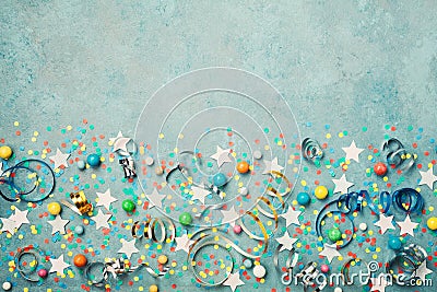 Holiday background decorated colorful confetti, star, candy and streamer on blue vintage table top view. Flat lay. Festive border. Stock Photo