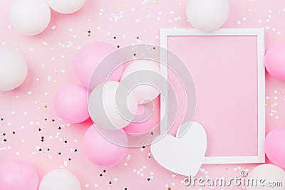 Holiday or birthday mockup with frame, pastel balloons, heart and confetti on pink table top view. Flat lay composition. Stock Photo