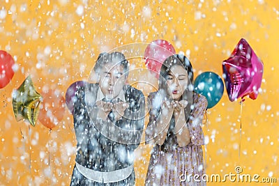 Holiday Celebrate, Christmas and New year party concept. Portrait of asian man and woman blowing silver paper confetti with Stock Photo