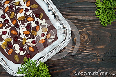 Holiday chocolate bark with dried fruits and nuts on a dark wood background. Top view. Dessert recipe for judaic holiday Tu Bishva Stock Photo