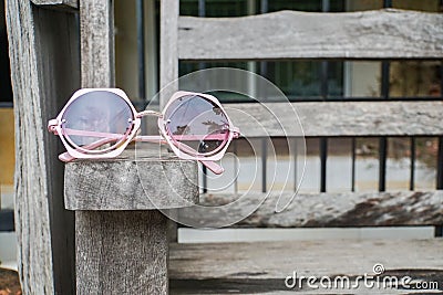 Cute pink women sunglasses on wooden bench Stock Photo