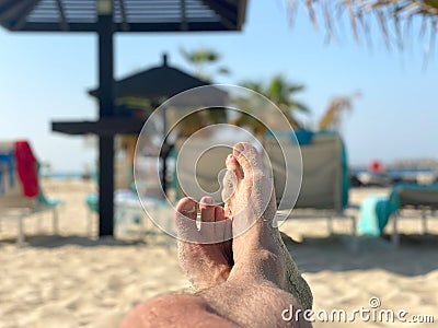 Holiday concept. male feet close-up relaxing on beach, enjoying sun and splendid view. Stock Photo