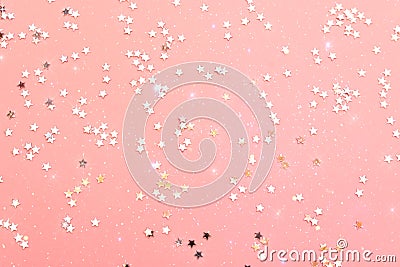 Holiday festive glitter background with pattern from scattered sparkling golden silver stars on pink backdrop. New Years Christmas Stock Photo