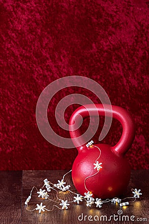 Holiday fitness, red kettlebell with white snowflake twinkle lights, against a red background Stock Photo