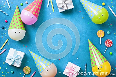 Holiday frame or background with funny balloons in caps, gifts, confetti, candy and candles. Flat lay. Birthday or party card. Stock Photo