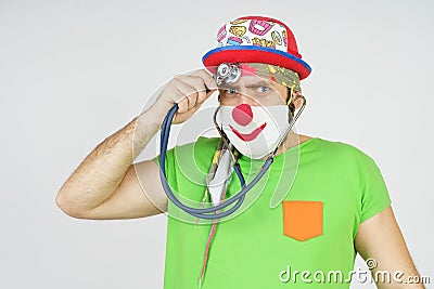 The clown is playing doctor, listening to his head with a stethoscope. Isolated on white Stock Photo
