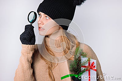 Holiday girl wearing black hat and gloves looking for Christmas discounts with magnifying glass. White background Stock Photo