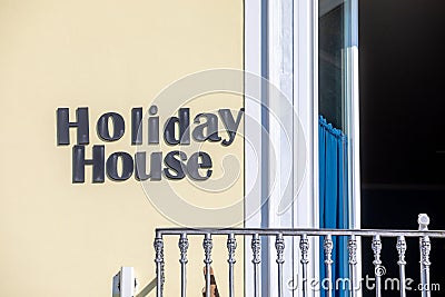 Holiday house. Hotel words text posted on the exterior wall. Near the railing of a balcony. Yellow wall Stock Photo