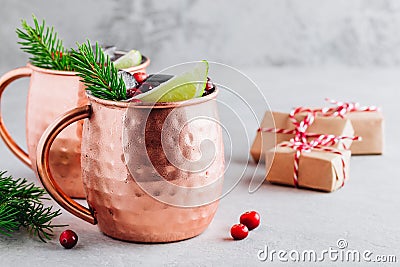 Holiday Moscow Mule ice cold Cocktail in copper cup with cranberries, lime and rosemary on stone background Stock Photo