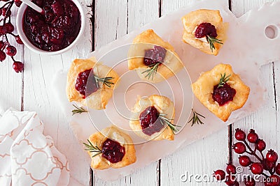 Holiday puff pastry appetizers with cranberries and baked brie, above view serving platter against white wood Stock Photo