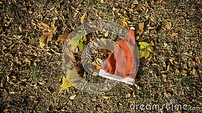 Holiday season is coming soon. A conceptual background photo of Santa Claus hat on yellow leaves in fall. Last day of autumn and Stock Photo