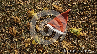 Holiday season is coming soon. A conceptual background photo of Santa Claus hat on yellow leaves in fall. Last day of autumn and Stock Photo