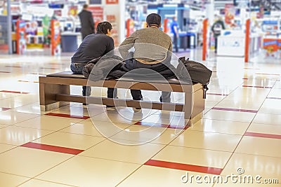 Holiday shopping men with women concept. two unrecognizable tired men are sitting on a bench in a shopping center Editorial Stock Photo