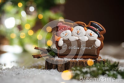 Holiday traditional food bakery. Gingerbread three fun snowmans in cozy warm decoration with garland lights Editorial Stock Photo