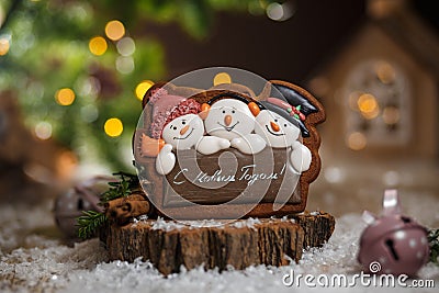 Holiday traditional food bakery. Gingerbread three fun snowmans in cozy warm decoration with garland lights Editorial Stock Photo