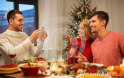 Happy friends photographing at christmas dinner Stock Photo