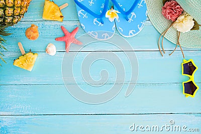 Pineapple slices, shells, starfish, slippers, straw hat and sunglasses on wood plank blue color. Stock Photo