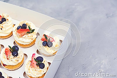 Holidays cupcakes with strawberry and blueberry, close up. Cupcakes packaging, delivery box on grey background. Gift box with Stock Photo