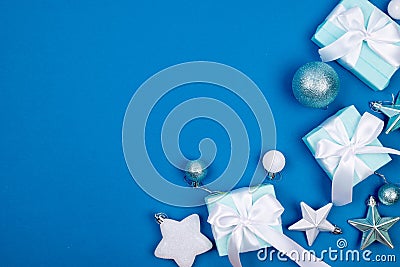 Holidays gift box wrapped in blue paper, balls, glitter on blue background Stock Photo