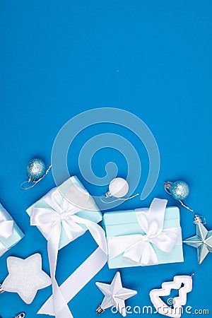 Holidays gift box wrapped in blue paper, balls, glitter on blue background Stock Photo