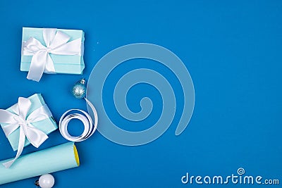 Holidays gift box wrapped in blue paper, balls, glitter on blue background Stock Photo