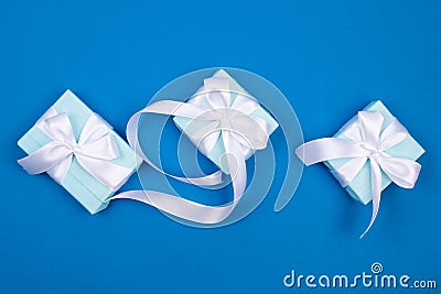 Holidays gift box wrapped in blue paper, balls, glitter on blue background Stock Photo