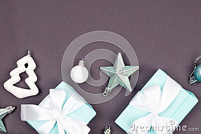 Holidays gift box wrapped in blue paper, balls, glitter on grey background Stock Photo