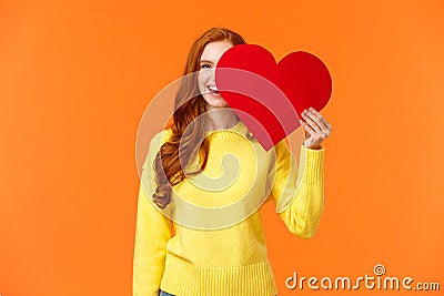 Holidays, romance concept. Cheerful girl showing affection, give heart to girlfriend, hiding half face behind valentines Stock Photo