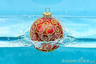 Holidays and vacation concept. Festive decoration for Christmas tree, red ball with glitter decor dropped into water Stock Photo