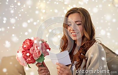 Happy woman with flowers and greeting card at home Stock Photo