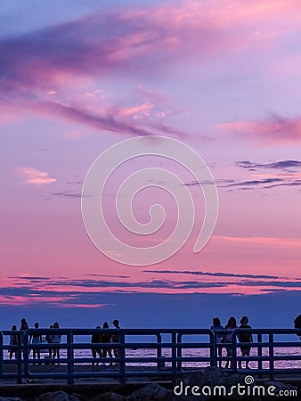 Holland, Michigan - 8/10/19: silouhette of people on pier enjoying pink sunset Editorial Stock Photo