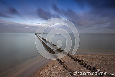 Holland - An old, dilapidated, wooden breakwater, begins on the edge of a sandy beach and ends in the sea. For a long time calmed Stock Photo