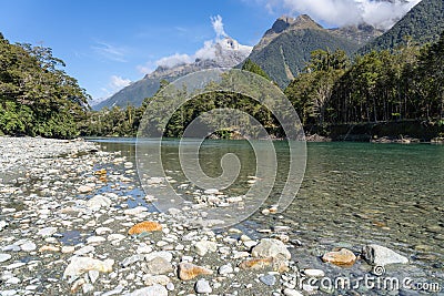 Hollyford River flowing between mountains over flat wide stony riverbed Stock Photo