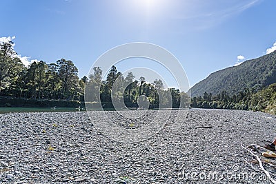 Hollyford River flowing between mountains over flat wide stony riverbed Stock Photo
