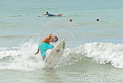 Surfers on the Beach Catching a Wave Editorial Stock Photo