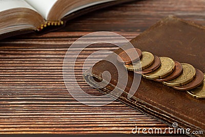 Holy bible book, stack of coin money, and old wallet on wooden table, Christian tithing concept Stock Photo