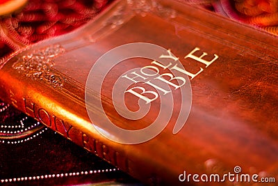 Holy Bible with pressed decorative leather cover on table with soft flickering candlelight Stock Photo