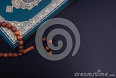 Holy Quran with arabic calligraphies translation meaning of Al-Quran and Rosary or Tasbih on black background Stock Photo