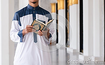 Holy Quran in Hand. Muslim man holding Quran Stock Photo
