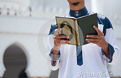 Holy Quran in Hand. Muslim man holding Quran Stock Photo