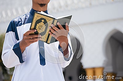 Holy Quran in Hand. Muslim man holding Quran Stock Photo