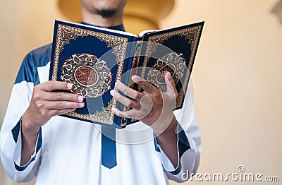 Holy Quran in Hand. Muslim man holding Quran Stock Photo