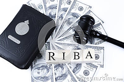 Holy Quran, judge gavel, money banknotes and wooden cubes with text RIBA Stock Photo