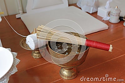 Holy water mixed and flower petals with perfume in a golden bowl by monk in Buddhist merit of Thai. For Blessing or Holy water in Stock Photo