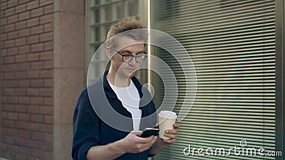 Hombre en vidrios que camina cerca del edificio de ladrillo, del café de consumición y de practicar surf de la web almacen de video Hombre en vidrios que camina cerca del edificio de ladrillo, del café de consumición y de practicar surf de la web almacen de video