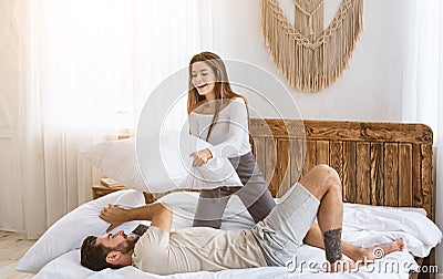 Home alone concept. Happy couple fights pillows, girl defeats guy Stock Photo