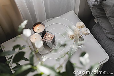 Home aroma fragrance diffuser and burning candles on bedside table in the bedroom. Cozy mood concept Stock Photo