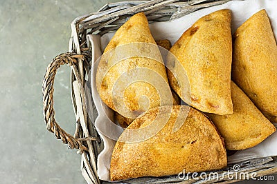 Home Baked Empanadas Turnover Pies with Pisto Vegetable Cheese Filling in Tomato Sauce in Wicker Basket. Spanish Pastry Dark Table Stock Photo