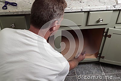 Adult Male Placing Clear Shelf Liner in a Bathroom Cabinet Stock Photo